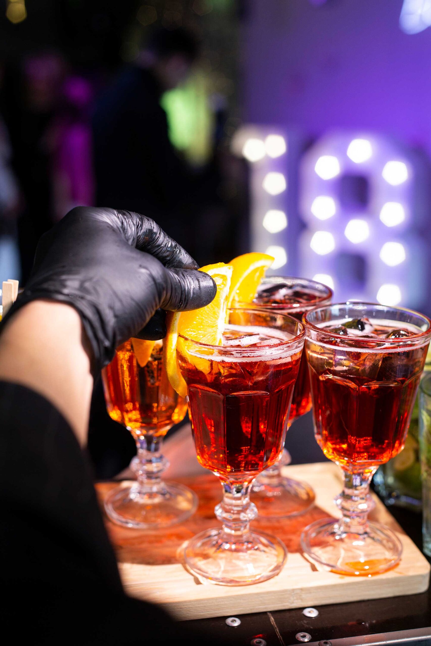 An expert garnishing cocktails with orange slices, showcasing the skills of mobile bartenders.