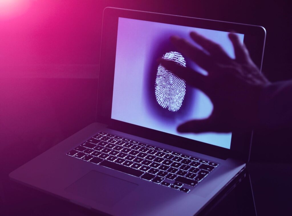 A concept for computer forensics displaying a large fingerprint on a computer screen with a man reaching his hand toward it.