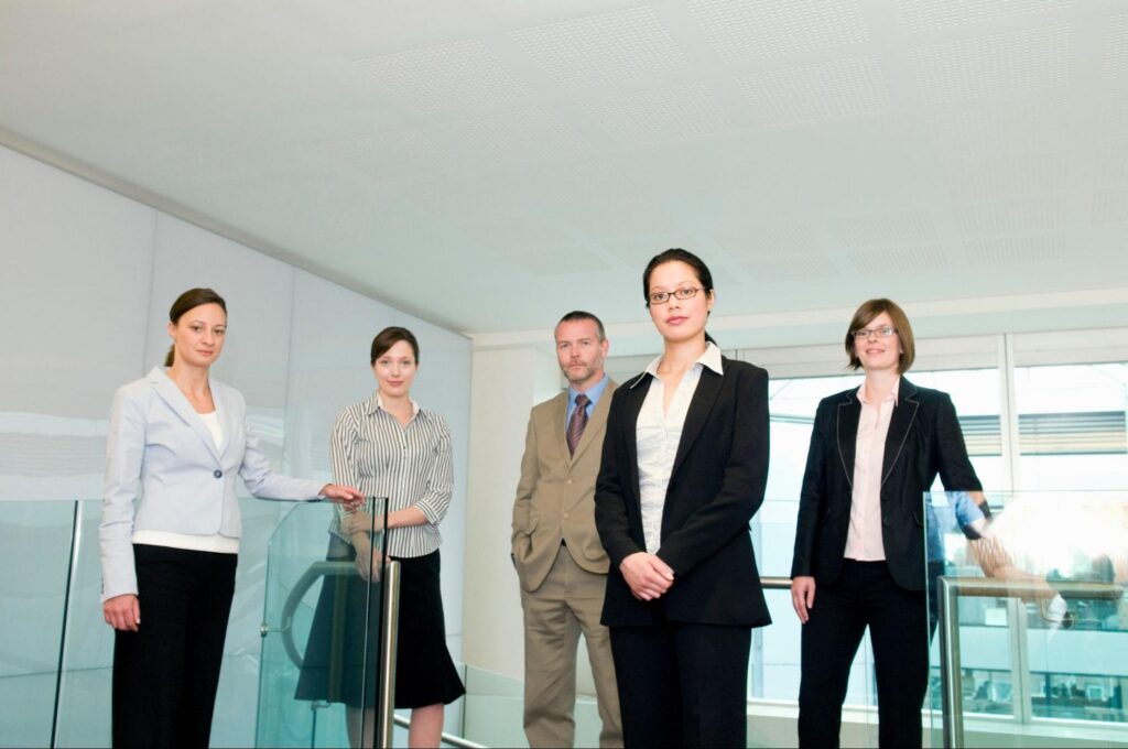 Five legal professionals stand together in their modern office.