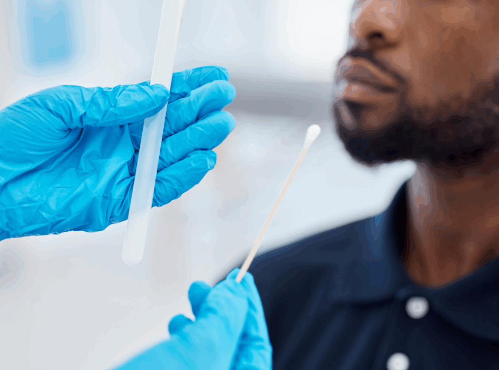 A medical professional holding a cotton swab in front of a man.
