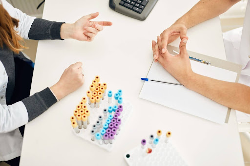 An overview of two people sitting on a table with bloodwork samples.