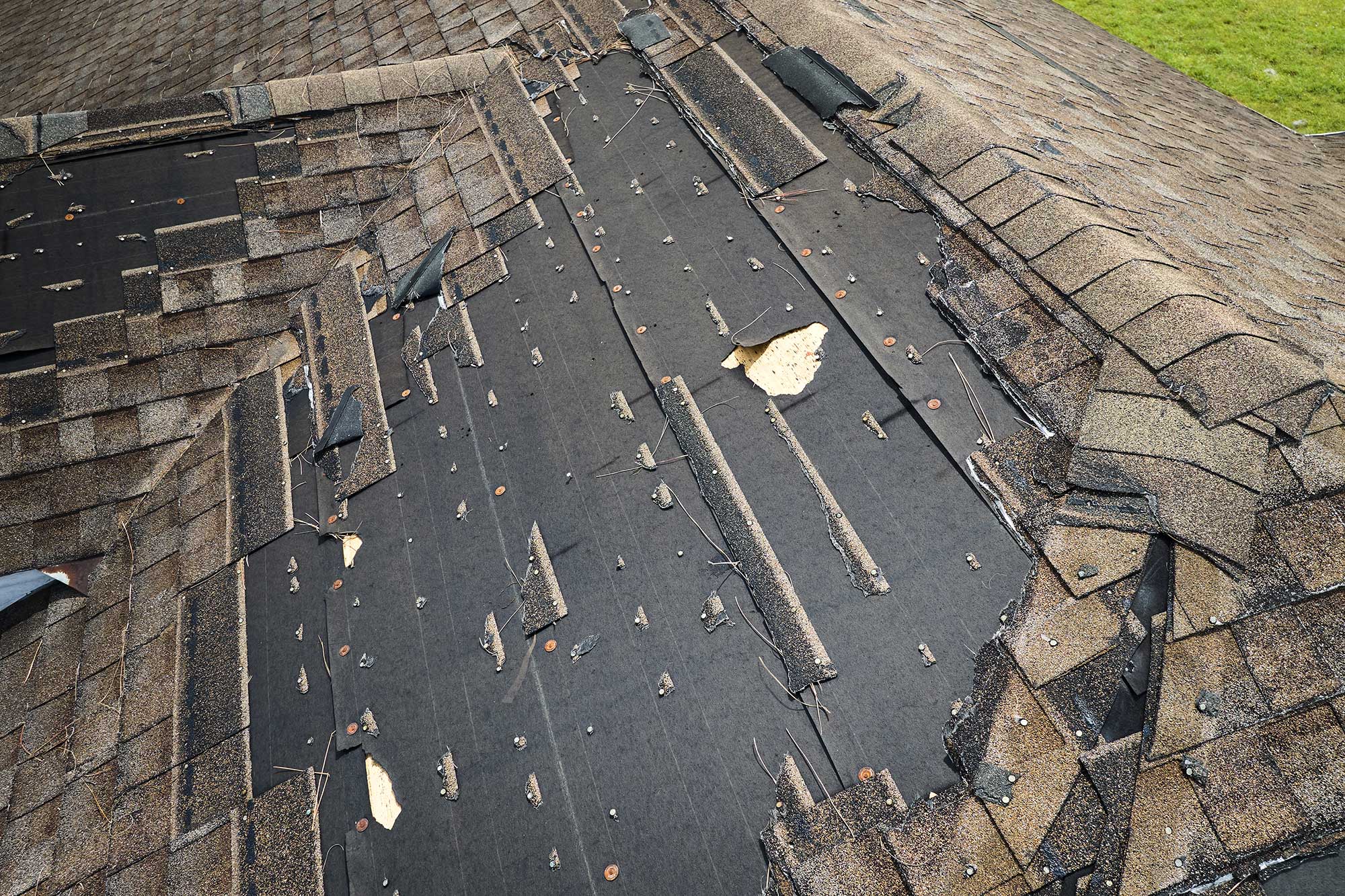 Damaged roof shingles on a residential home needing roofing services.