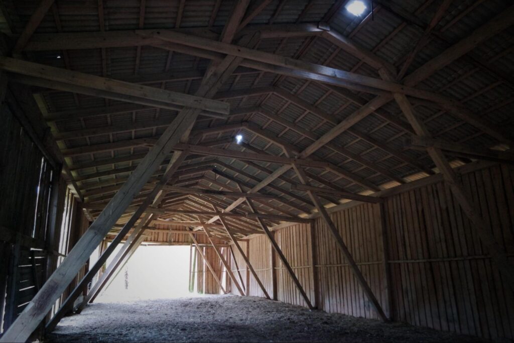 Inside a wooden barn with vaulted ceilings.