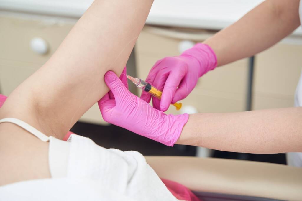Partial view of a female client receiving peptide injections in the arm to assist with focused fat-reduction goals