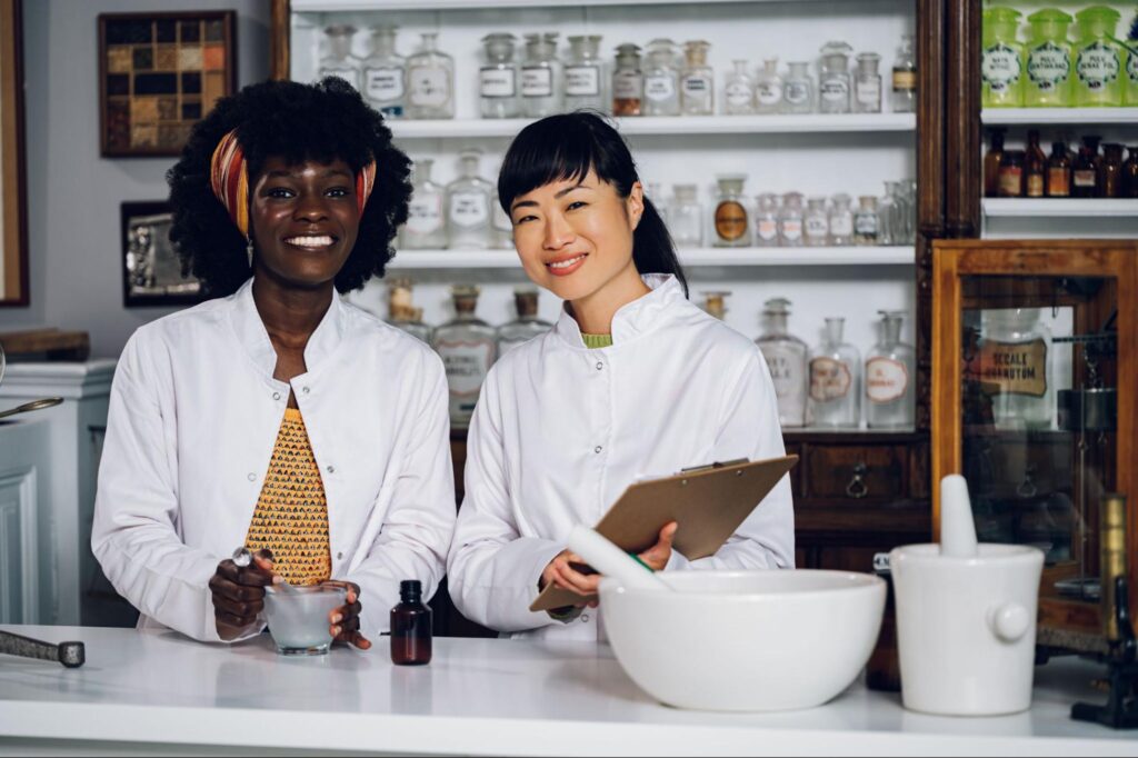 African-American and Asian apothecaries make herbal medicines in an apothecary shop.
