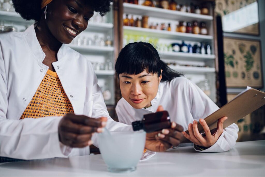An Asian senior apothecary checks the work of a young apothecary.