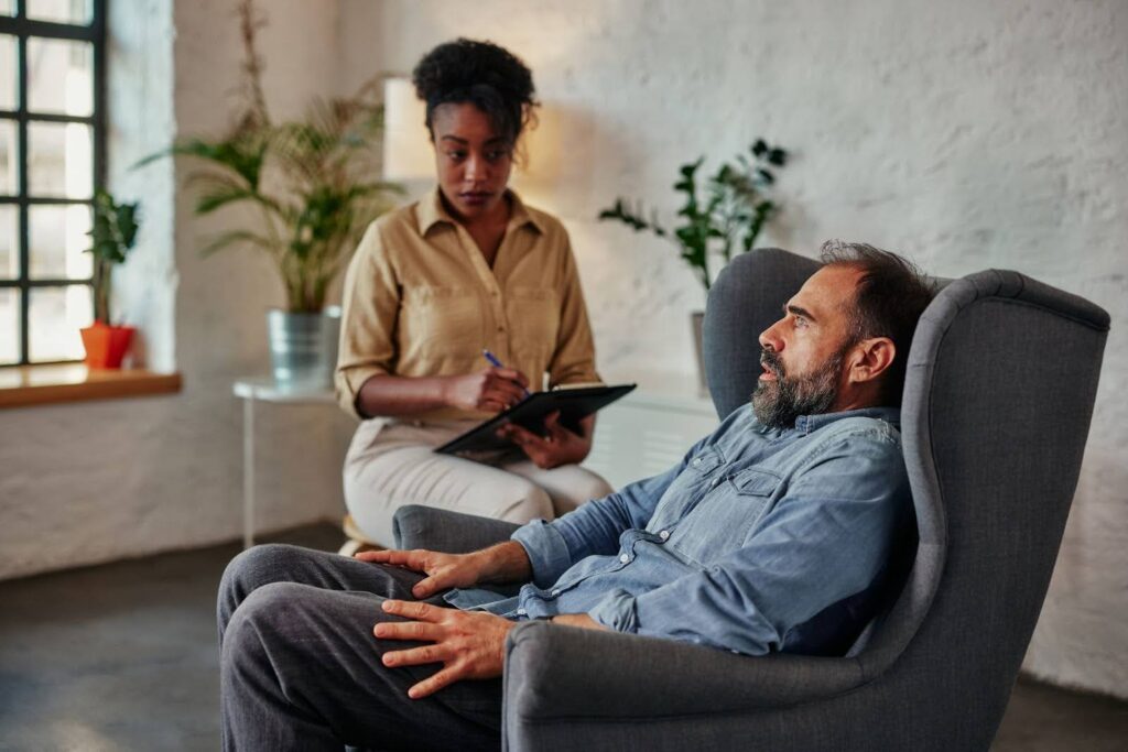 African female therapist providing therapy for mental health to a middle-aged businessman.