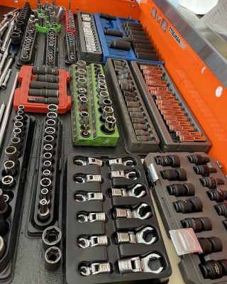 A neatly organized tool tray featuring various sockets, wrenches, and accessories in colorful trays for easy access and identification.
