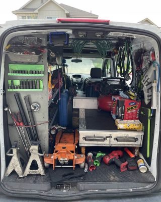 A van with various tools visible in the back, indicating it is used for maintenance or repair work.