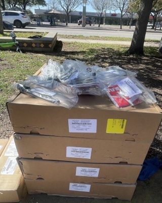 A pile of boxes on the ground beside a parked car, indicating a potential moving or delivery scenario.