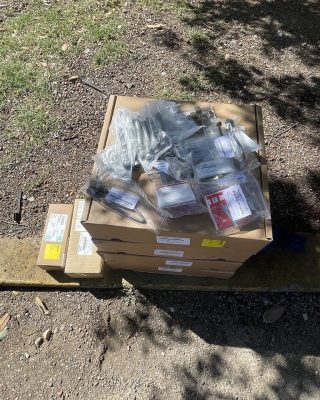A box of tools rests on the ground beside a tree, surrounded by grass and fallen leaves.