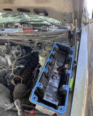 Car engine with a blue cover, showcasing mechanical components and design details.