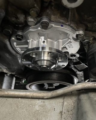 Car engine featuring a water pump and hose, showcasing components for cooling and fluid circulation.