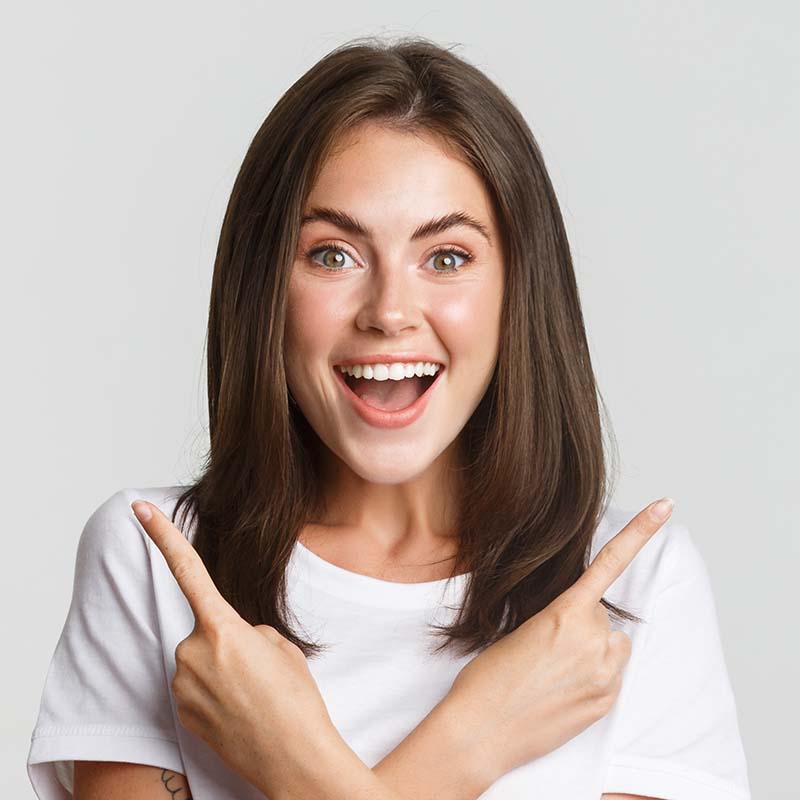 Woman looking at the camera smiling with shoulder length brown hair and her arms crossed
