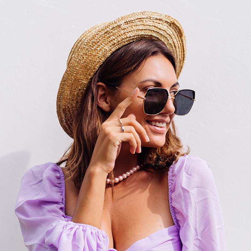 Woman in a hat and sunglasses in a purple top