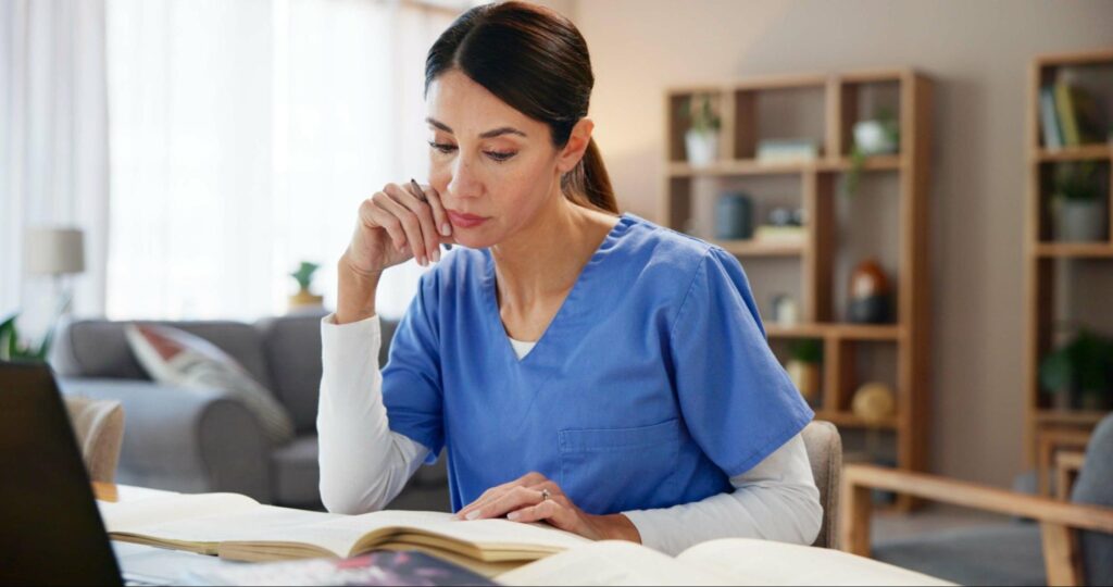 Nurse using textbook and laptop to plan care based on medical research and evidence.