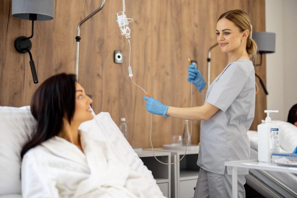 Nurse preparing an IV for a woman in a robe.