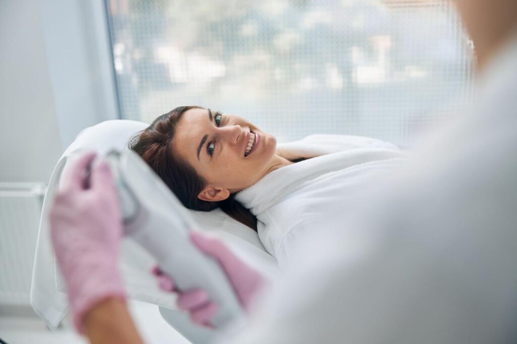 Woman lying down next to a technician at a med spa.