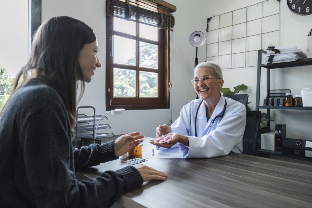 An elderly female doctor in a white coat discusses advanced integrative medicine with a young female patient in a clinic, providing personalized health advice.