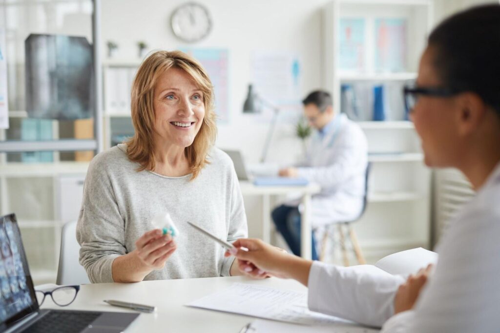 A mid-50s blonde woman consults a doctor about hormone replacement therapy.
