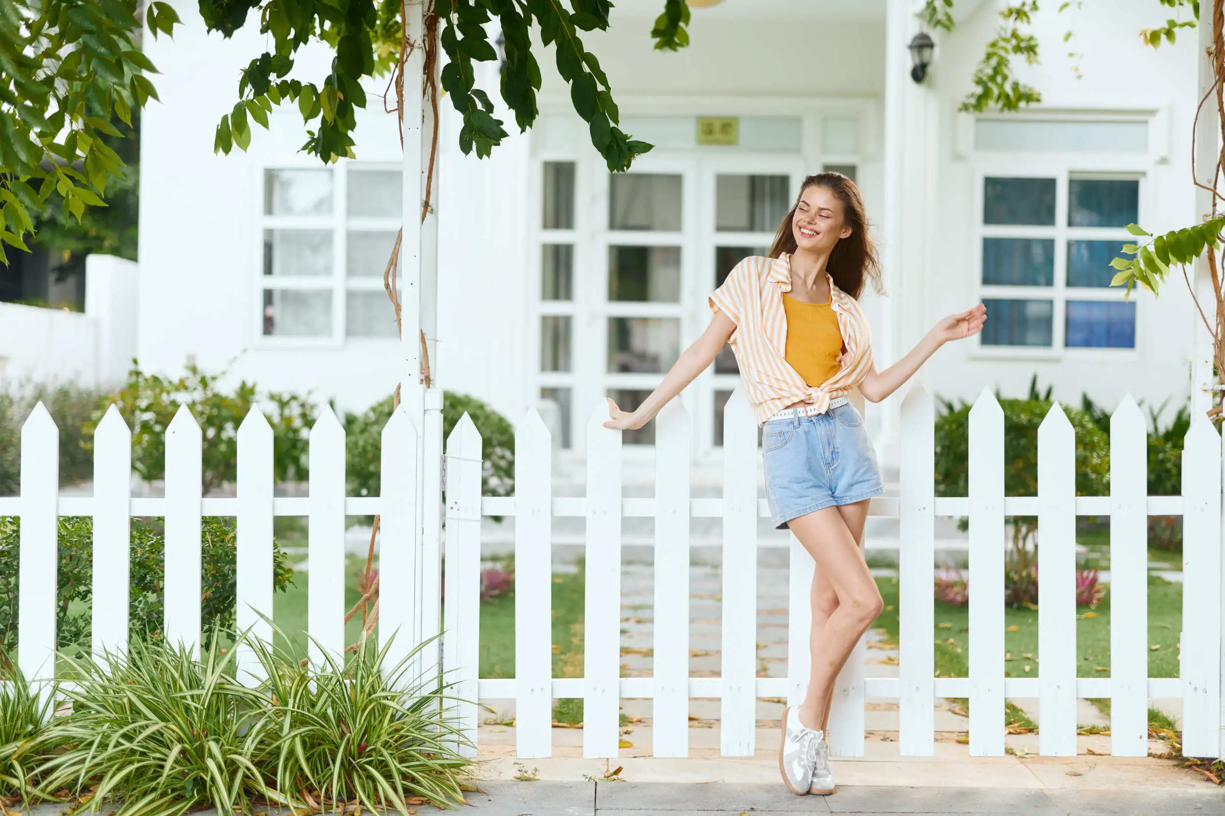 A woman standing by the white fence smiling.