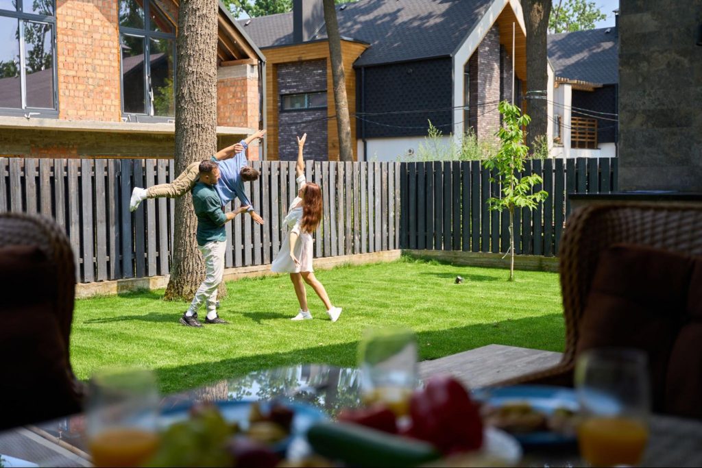 Family playing in a yard surrounded by fencing. 