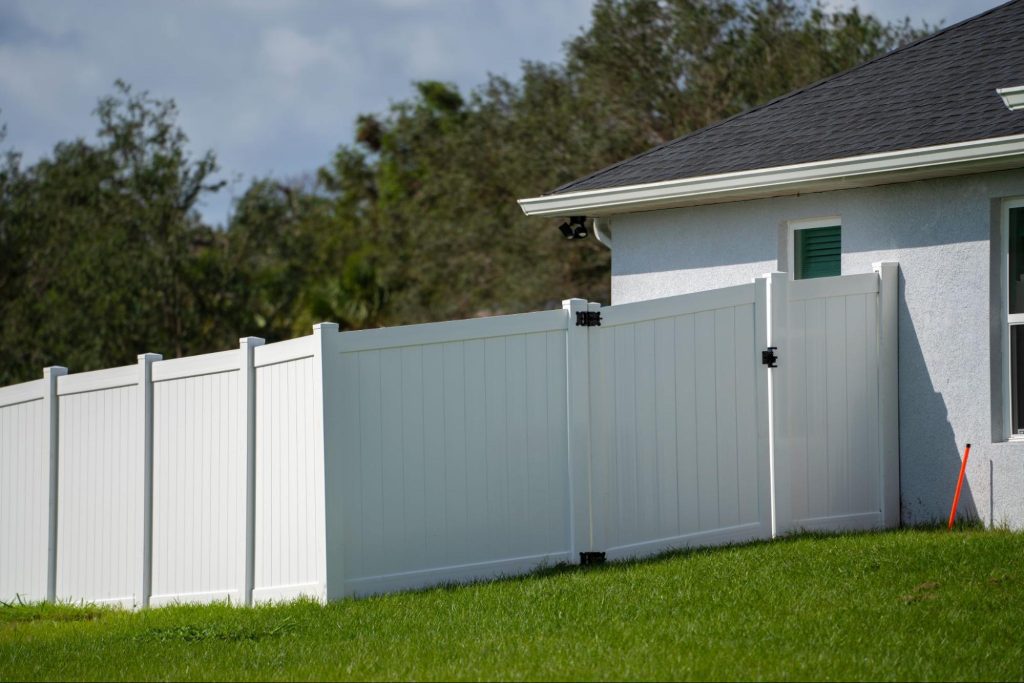 Vinyl fence with a gate next to a home.