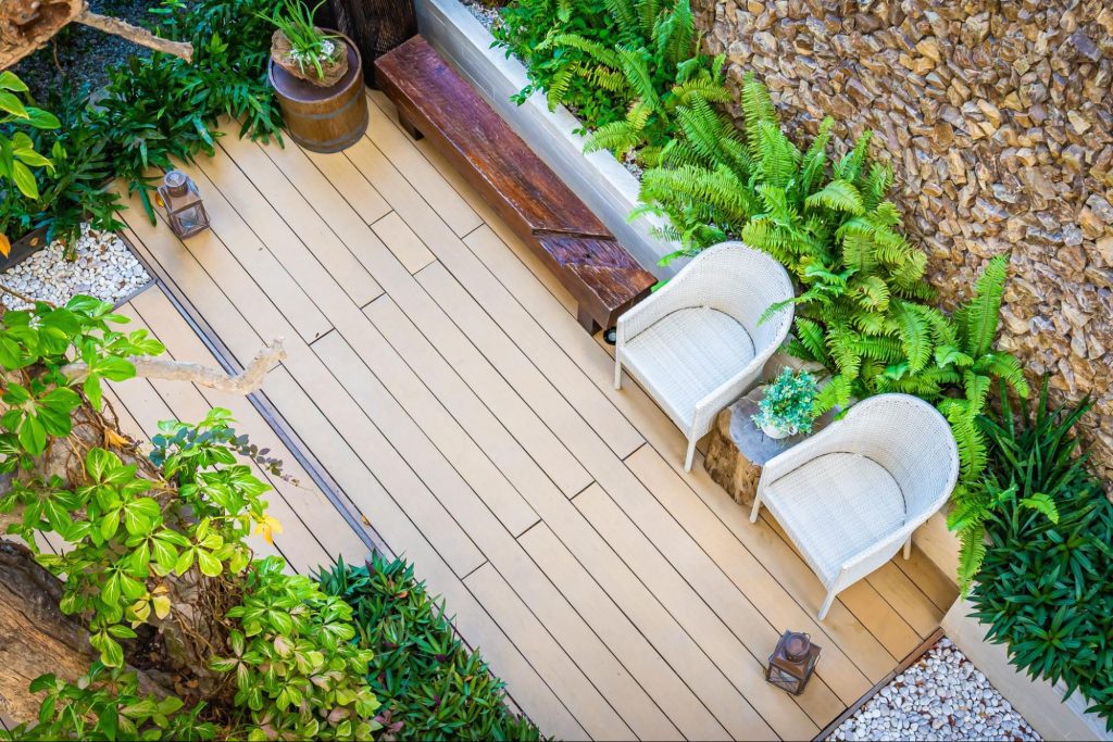A custom deck design featuring a wood floor, chairs, plants, and rock landscaping.