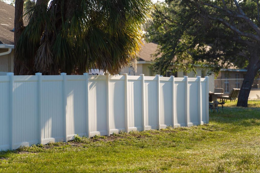 Vinyl fencing around a home next to trees.