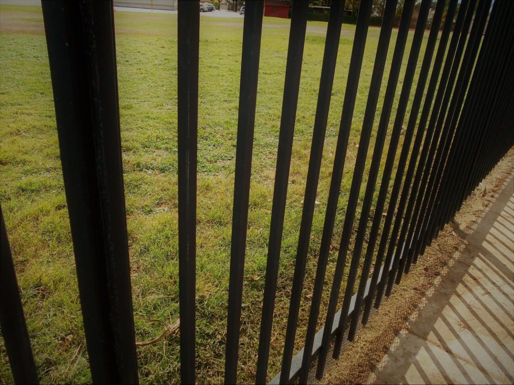 Aluminum fencing around a home with grass.