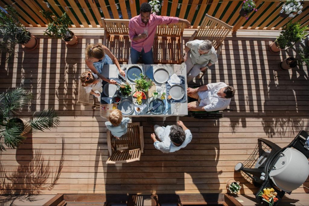 An aerial view of friends eating lunch on a deck.