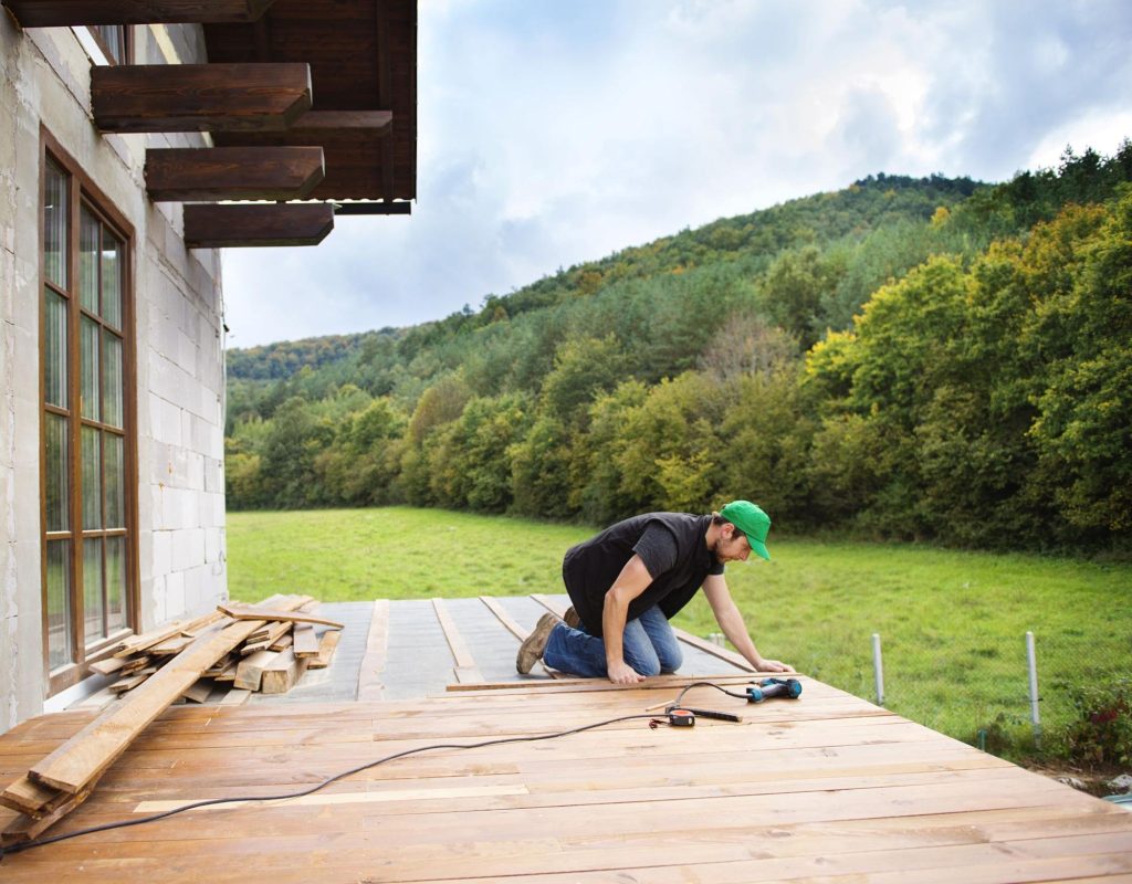 Man in a hat installing a deck.