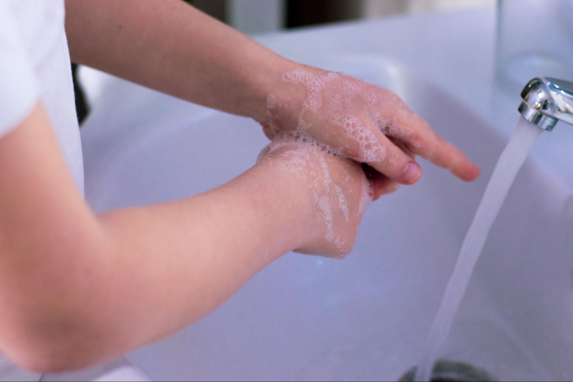 A doctor washing his hands thoroughly with soap and water in a sink.