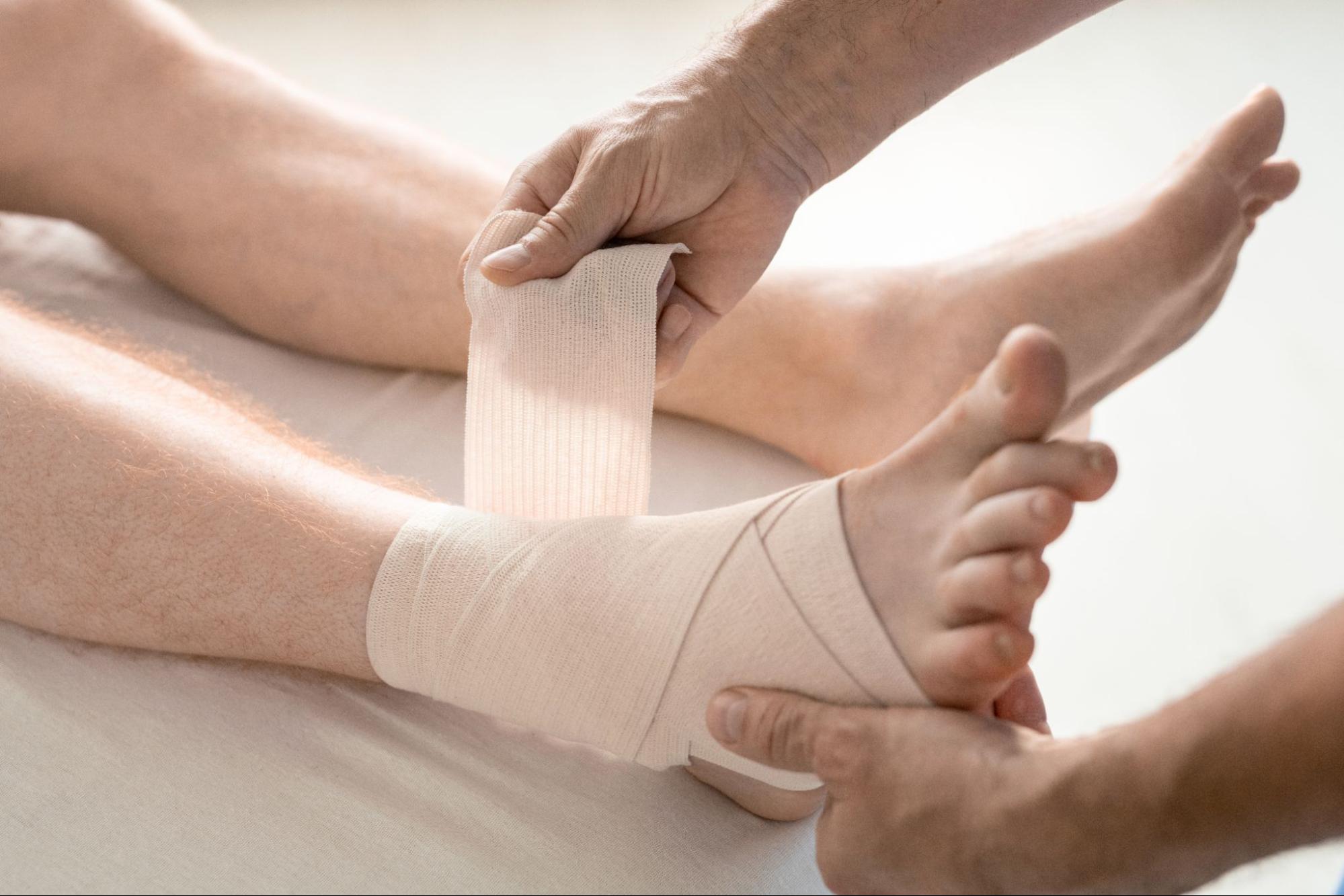 A doctor bandaging a pressure ulcer on a man’s foot.