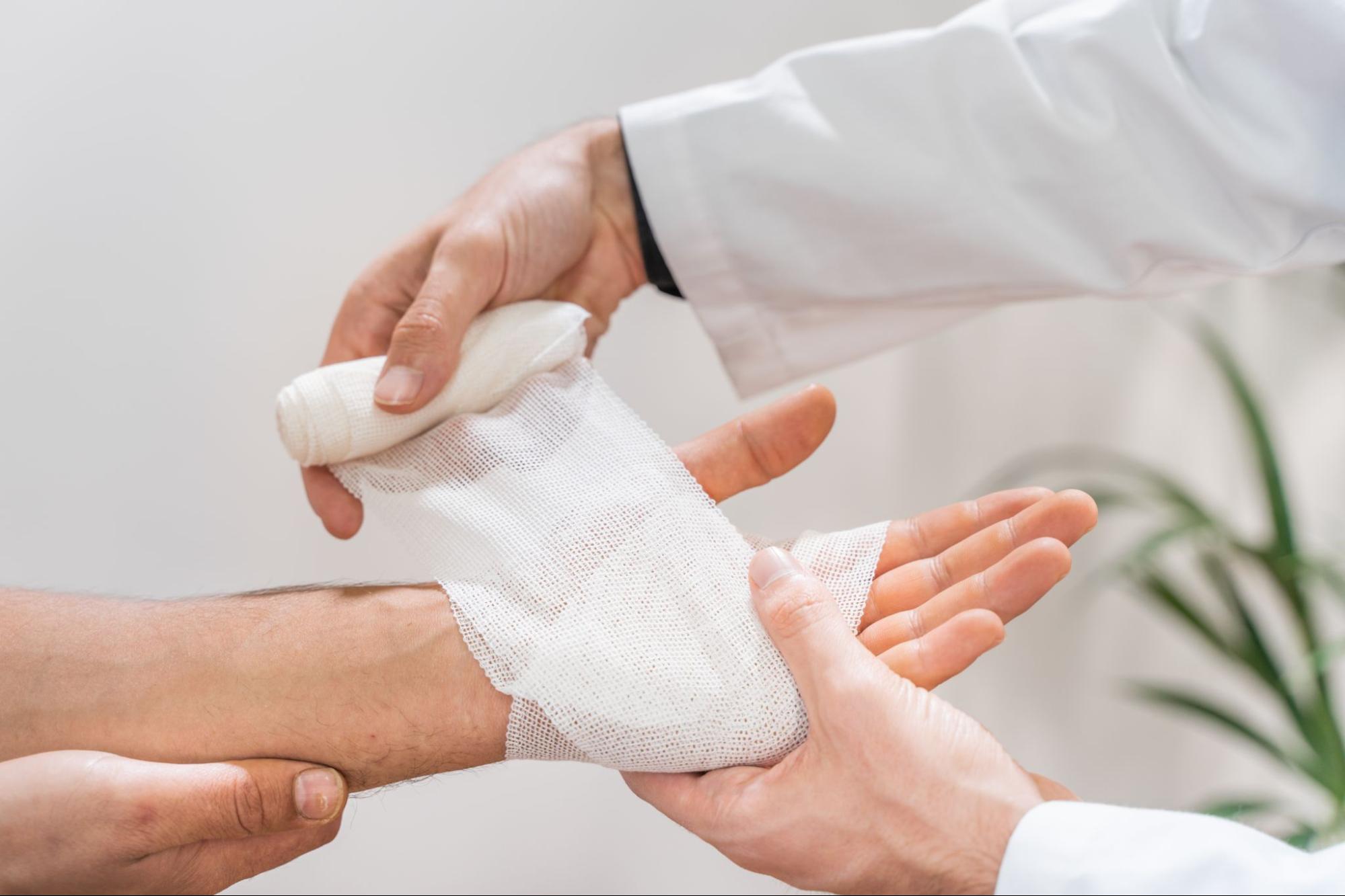 A doctor wrapping a medical bandage around a patient’s hand.