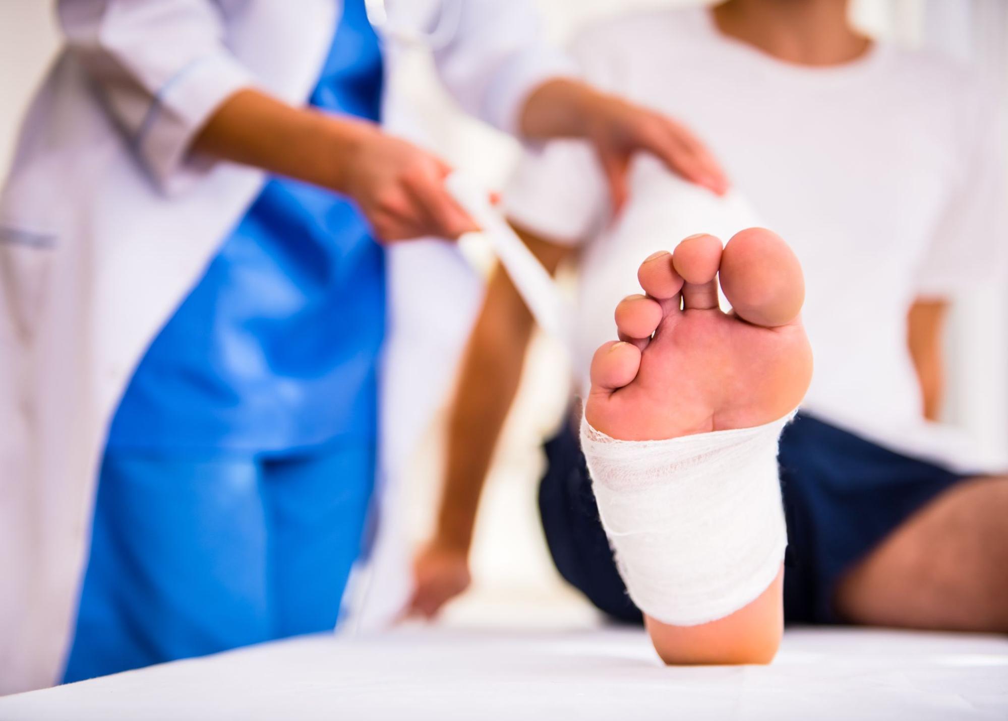 A nurse wrapping a chronic wound on a man's foot with a medical bandage.