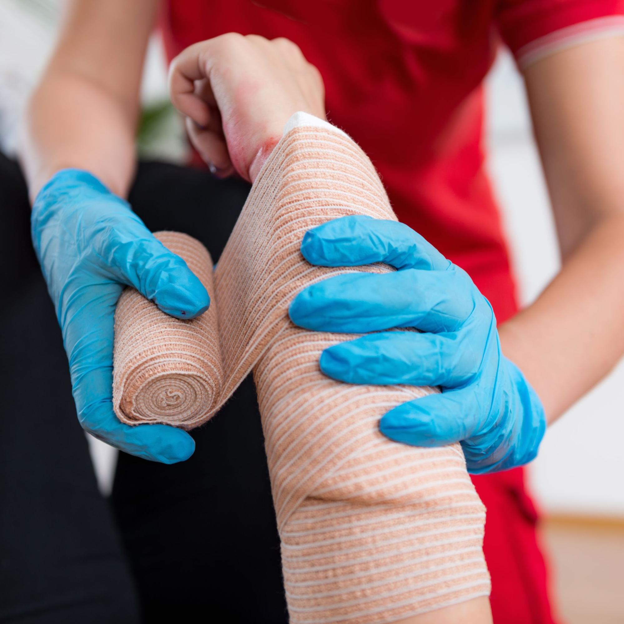 person in gloves adding gauze to a wound. 