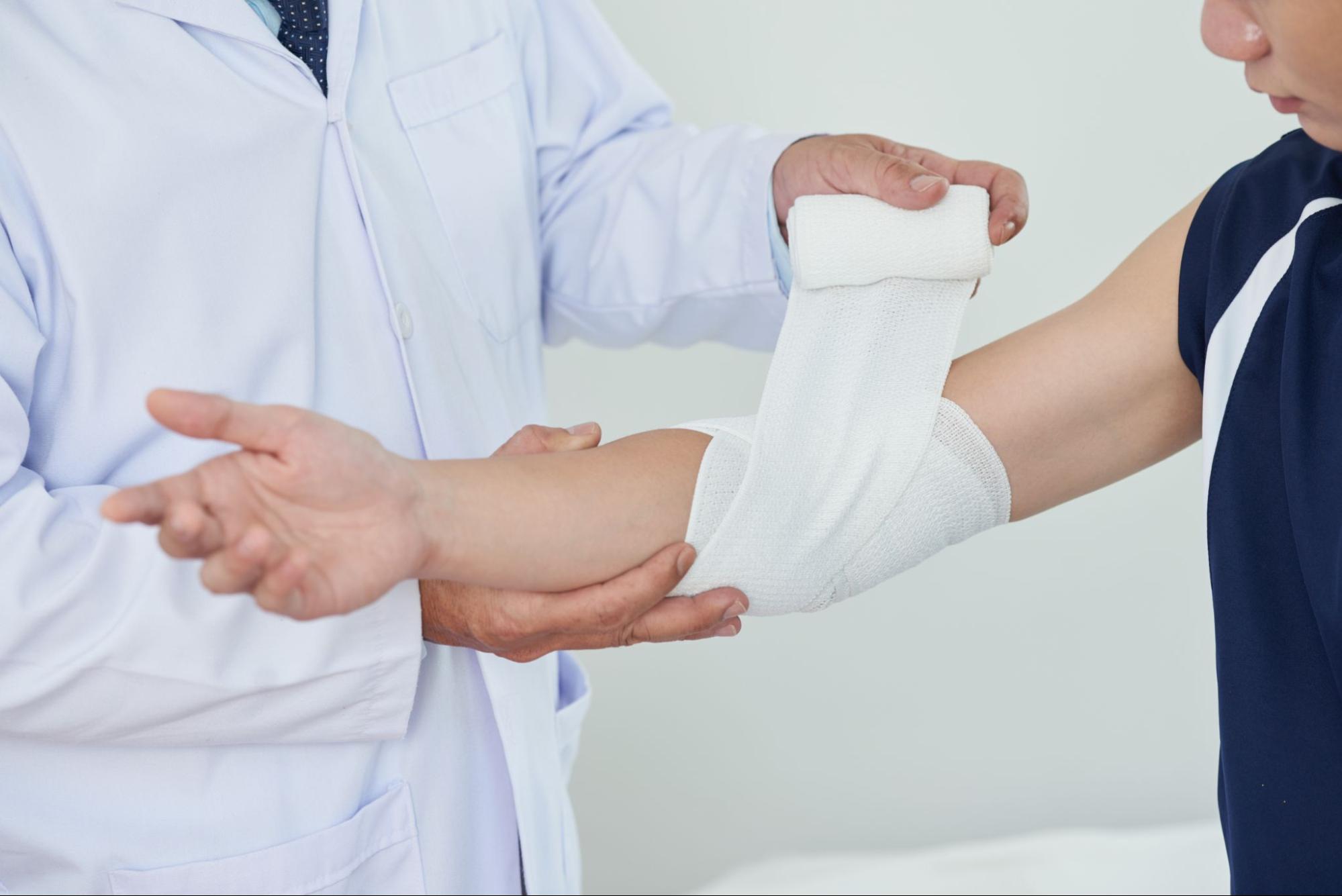 A doctor bandaging a pressure ulcer on a patient's elbow.