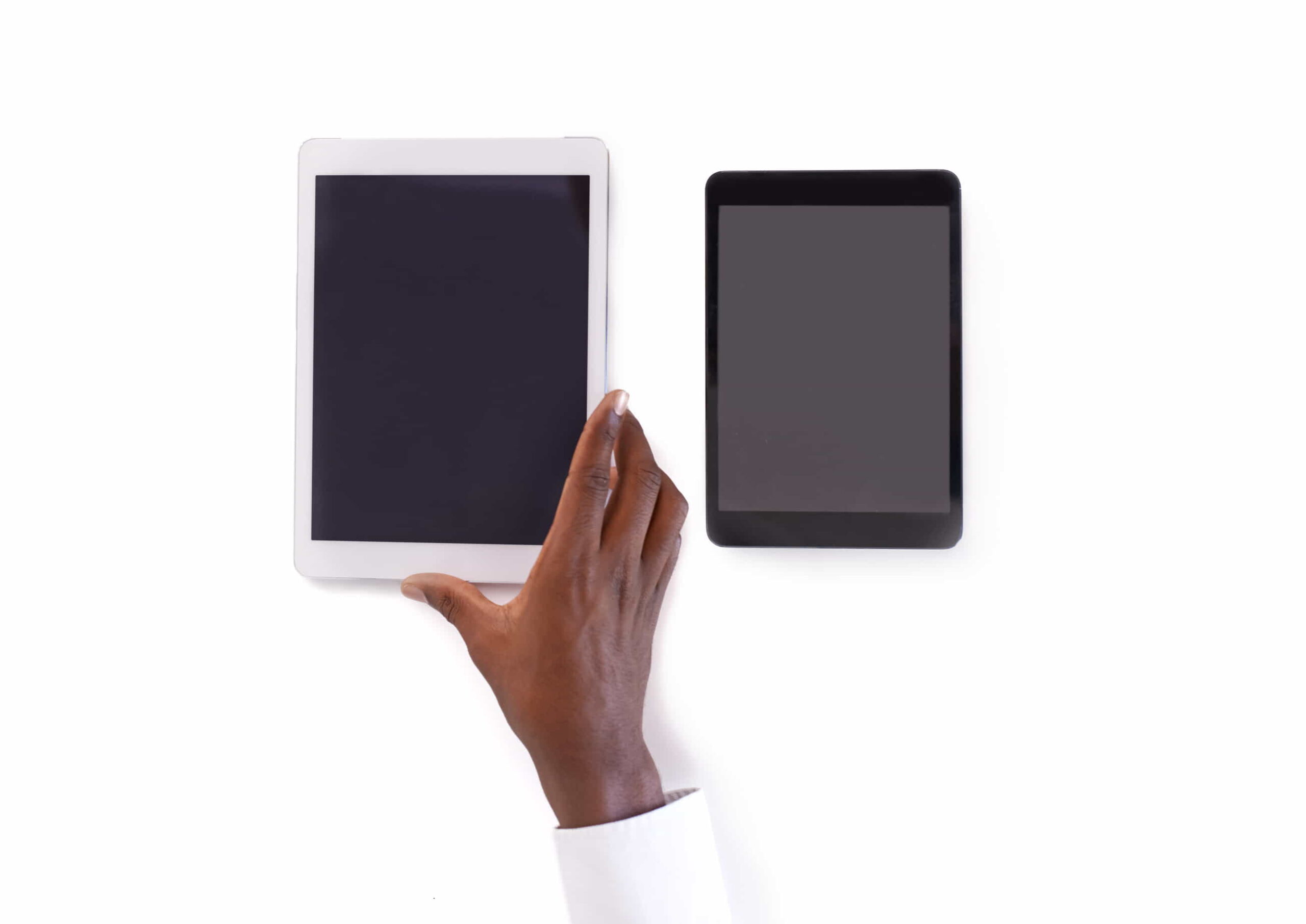 Cropped shot of a hand holding a white digital tablet, next to a black digital tablet